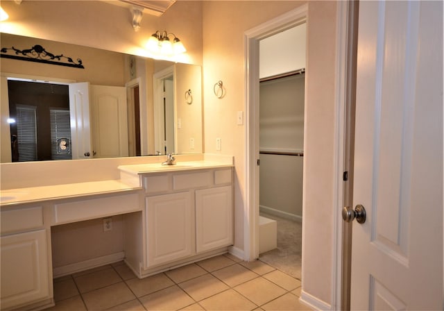 bathroom featuring tile patterned flooring, double vanity, baseboards, and a walk in closet