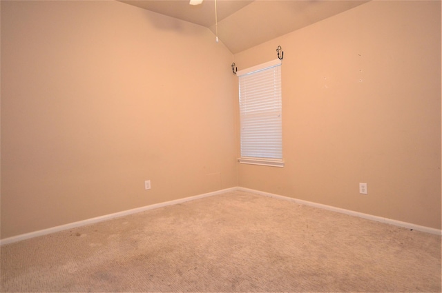 empty room featuring light carpet, vaulted ceiling, baseboards, and a ceiling fan