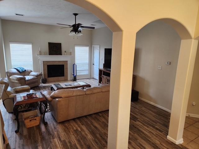 living area featuring ceiling fan, dark wood-style floors, plenty of natural light, and a tile fireplace