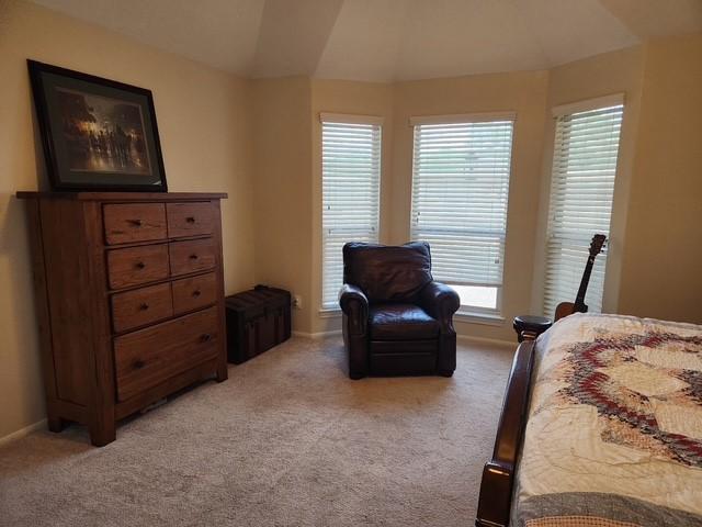 bedroom with light colored carpet, multiple windows, vaulted ceiling, and baseboards