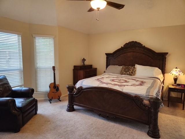 carpeted bedroom with ceiling fan, lofted ceiling, and baseboards