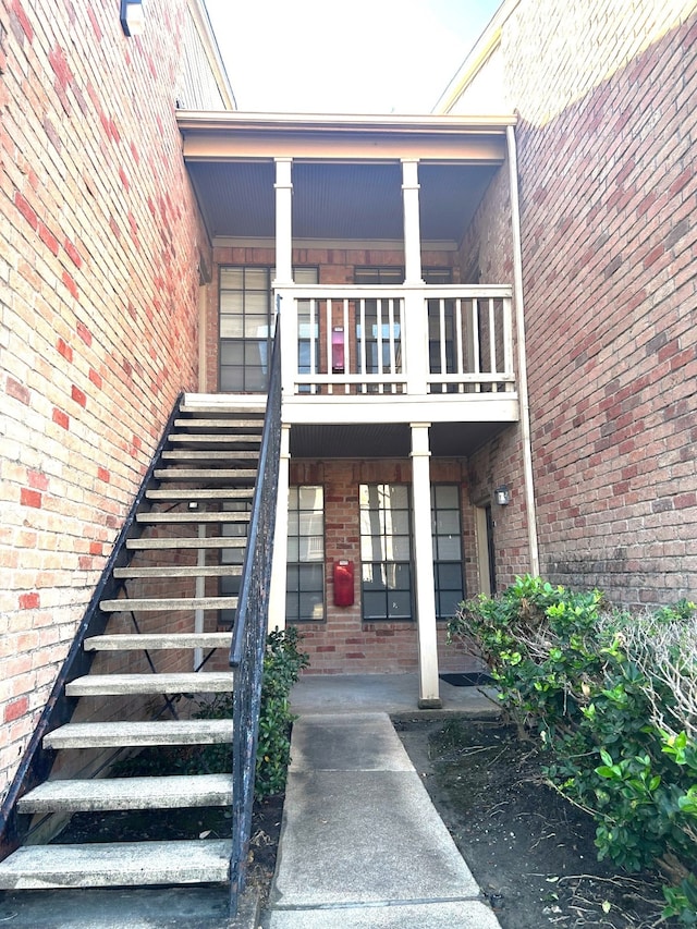 doorway to property featuring a balcony and brick siding