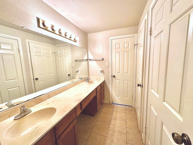 bathroom featuring a textured ceiling, double vanity, and tile patterned floors