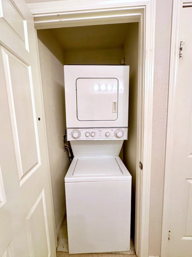 laundry room with stacked washer / drying machine and baseboards