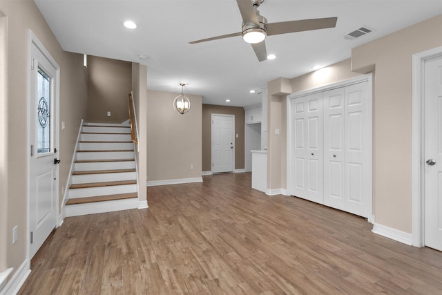 unfurnished living room featuring light wood-style floors, ceiling fan, baseboards, stairs, and recessed lighting