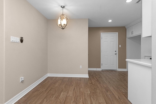 unfurnished dining area featuring wood finished floors, recessed lighting, baseboards, and a chandelier