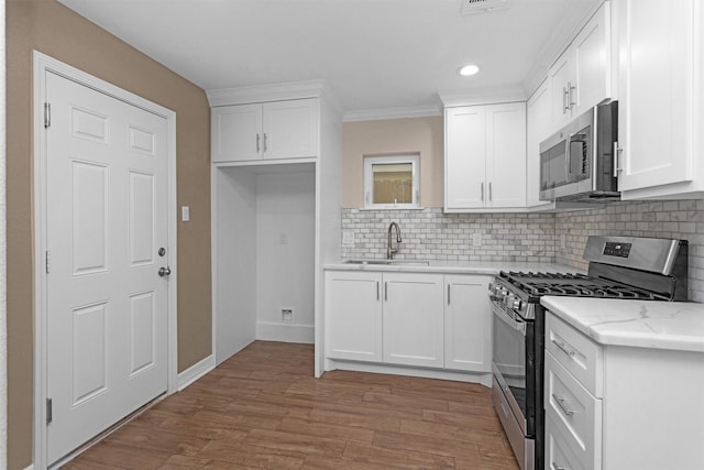 kitchen featuring appliances with stainless steel finishes, a sink, backsplash, white cabinetry, and recessed lighting