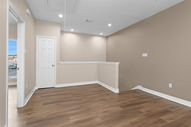 spare room featuring attic access, wood finished floors, baseboards, and recessed lighting