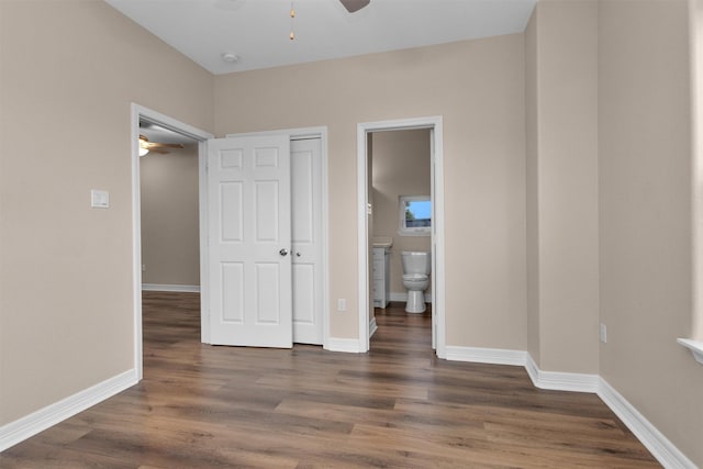 unfurnished bedroom with wood finished floors, baseboards, ensuite bathroom, and ceiling fan