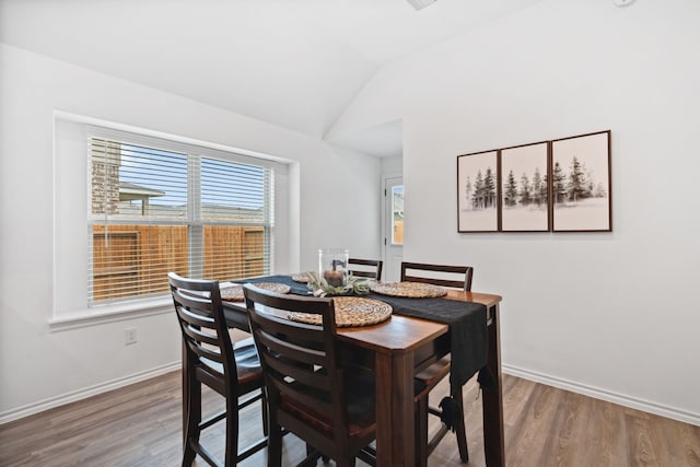 dining room with wood finished floors, lofted ceiling, and baseboards