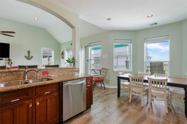 kitchen featuring dishwasher, a sink, healthy amount of natural light, light wood finished floors, and vaulted ceiling
