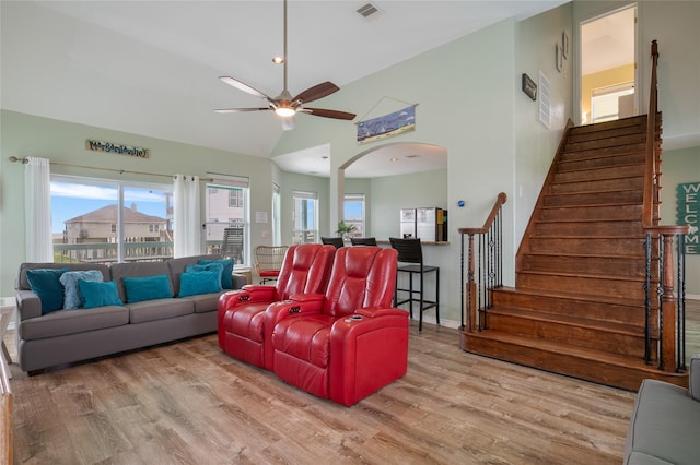 living area with ceiling fan, wood finished floors, arched walkways, stairway, and healthy amount of natural light