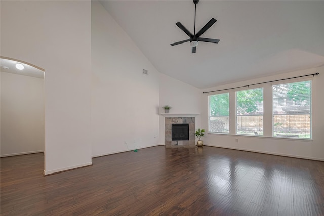 unfurnished living room with a ceiling fan, high vaulted ceiling, dark wood-type flooring, a tile fireplace, and baseboards