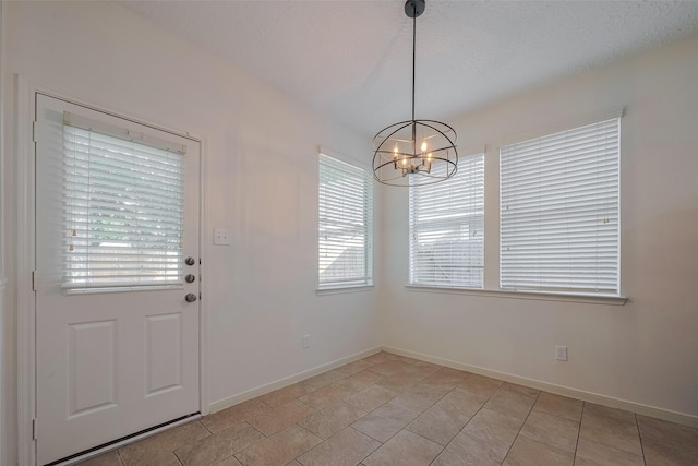 unfurnished dining area featuring healthy amount of natural light, a chandelier, and baseboards