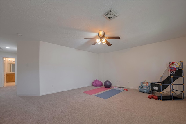 exercise area with carpet flooring, ceiling fan, baseboards, and a textured ceiling