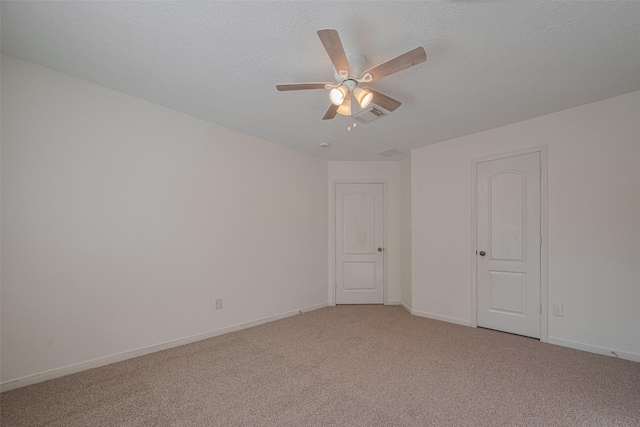 spare room with light carpet, ceiling fan, baseboards, and a textured ceiling