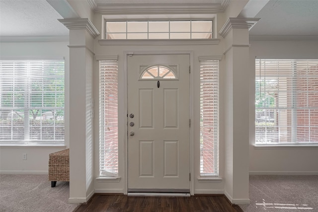 foyer with baseboards, ornamental molding, ornate columns, and dark colored carpet