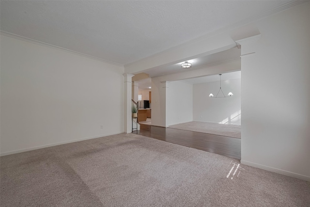 spare room with carpet, ornate columns, a chandelier, ornamental molding, and baseboards