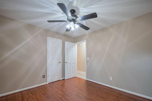194 Velvet Leaf Pl, The Woodlands, TX 77380 - unfurnished bedroom with wood finished floors, baseboards, ceiling fan, and a textured ceiling