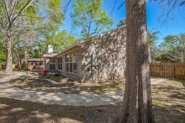 194 Velvet Leaf Pl, The Woodlands, TX 77380 - view of home's exterior featuring fence, a chimney, and brick siding