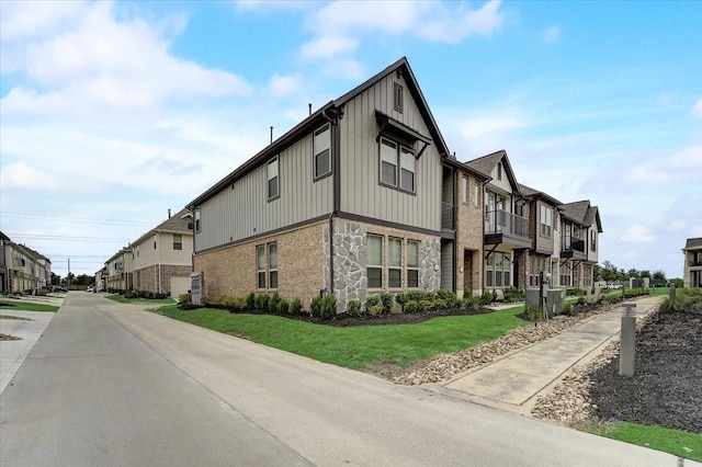 9438 Caddo Ridge Ln, Cypress, TX 77433 - view of property exterior with a residential view, stone siding, board and batten siding, and a lawn
