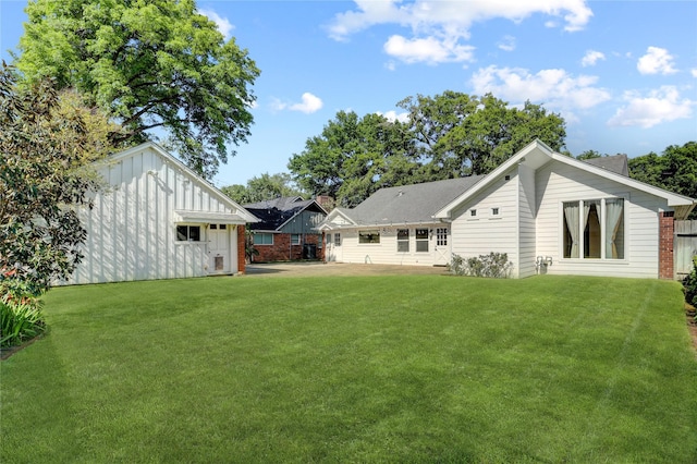 rear view of property with board and batten siding, a yard, and an outbuilding