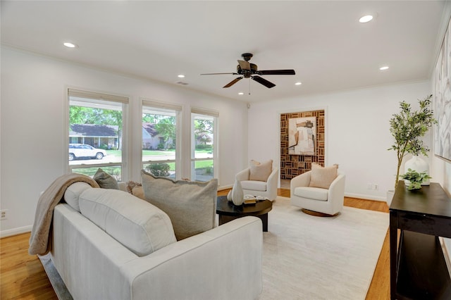 living area featuring light wood-type flooring, a ceiling fan, recessed lighting, ornamental molding, and baseboards