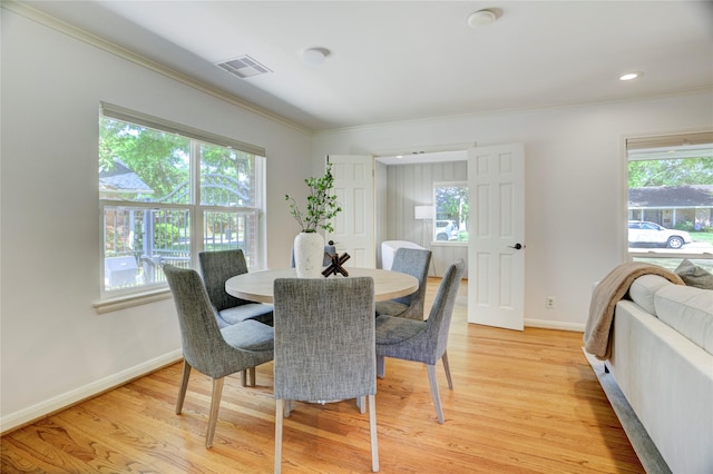 dining area with ornamental molding, light wood-style flooring, and baseboards