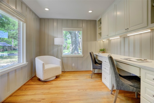 office space featuring built in study area, a decorative wall, light wood-style floors, and recessed lighting