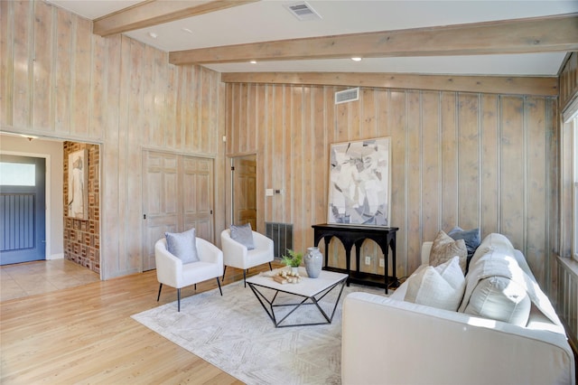 living area featuring wood walls, beam ceiling, and wood finished floors