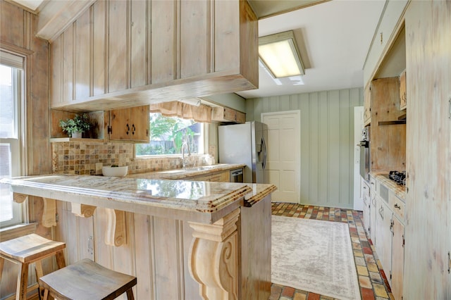 kitchen with stainless steel appliances, brick patterned floors, a peninsula, backsplash, and plenty of natural light