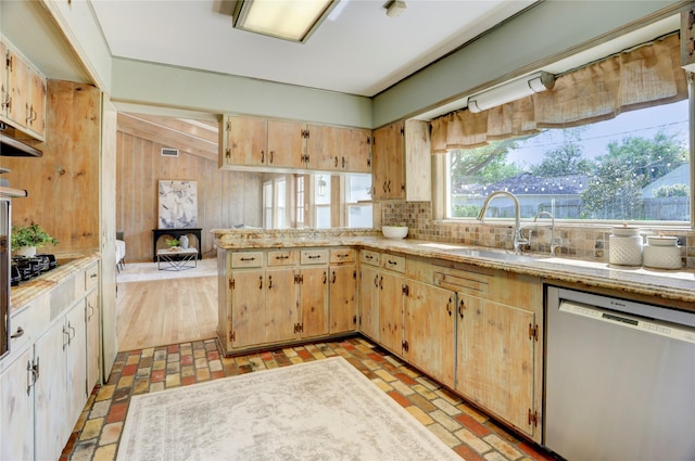 kitchen with stainless steel dishwasher, a sink, backsplash, a peninsula, and light brown cabinetry