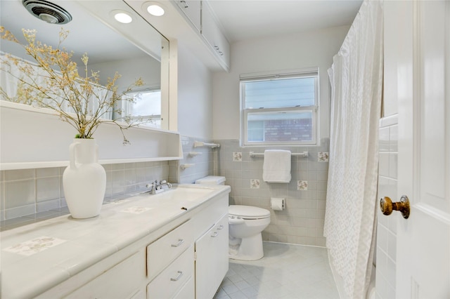 full bath featuring toilet, plenty of natural light, tile walls, tile patterned floors, and vanity