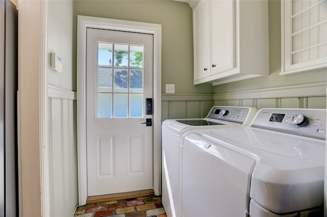 laundry area featuring independent washer and dryer, cabinet space, wainscoting, and a decorative wall