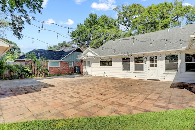 rear view of house featuring a patio area, a shingled roof, and fence