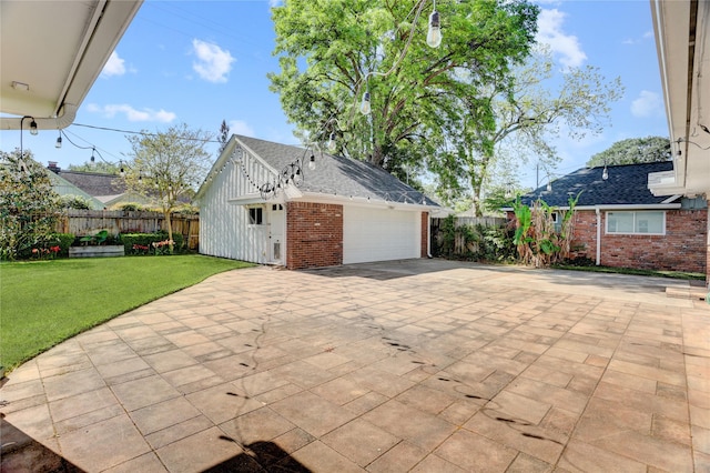 view of home's exterior featuring brick siding, a shingled roof, an outdoor structure, driveway, and an attached garage