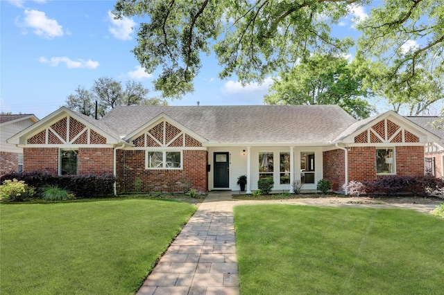 view of front facade featuring a front yard, brick siding, and roof with shingles
