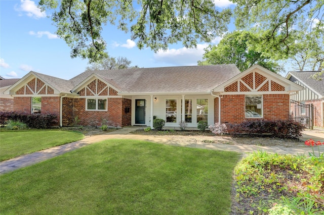 view of front of house with brick siding, a front yard, and roof with shingles