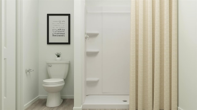 bathroom with baseboards, a shower stall, wood finished floors, and toilet