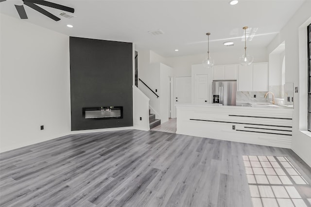 8888 Benning Dr Unit 313, Houston, TX 77031 - unfurnished living room featuring light wood-style flooring, a sink, a ceiling fan, stairs, and recessed lighting