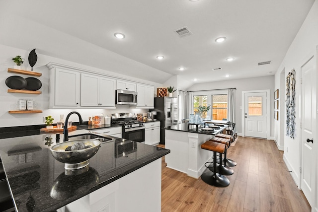 kitchen featuring appliances with stainless steel finishes, a kitchen breakfast bar, a sink, a center island, and light wood-style flooring