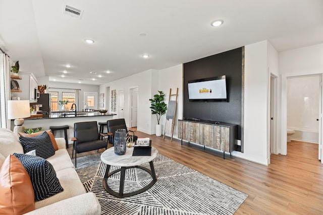 living room with light wood-style floors, baseboards, and recessed lighting