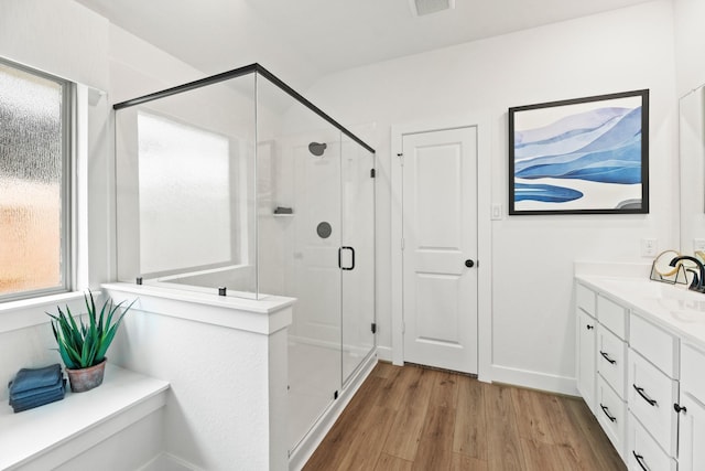bathroom featuring wood finished floors, a shower stall, and vanity