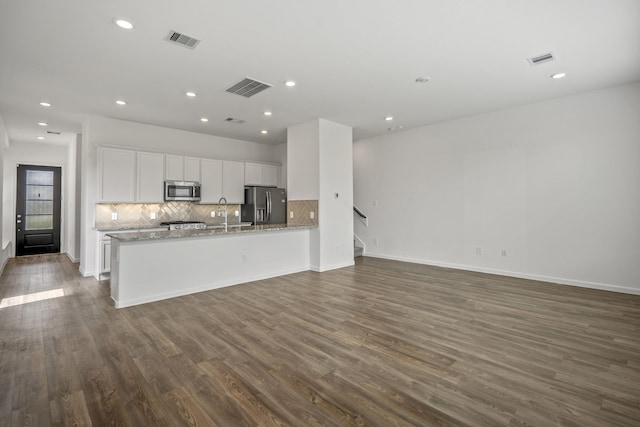 kitchen featuring stainless steel appliances, white cabinets, decorative backsplash, dark wood-style floors, and open floor plan