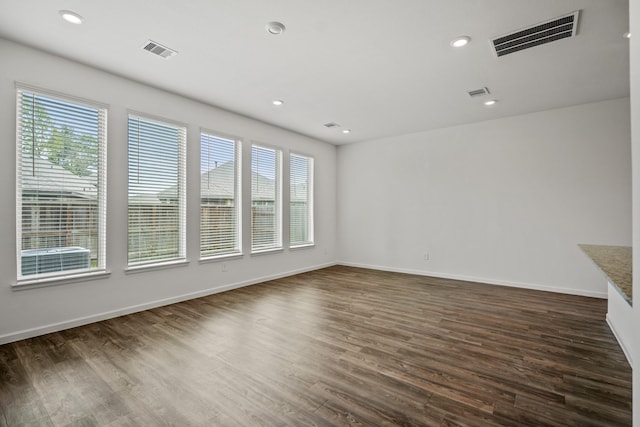 unfurnished living room featuring healthy amount of natural light, dark wood-type flooring, baseboards, and recessed lighting