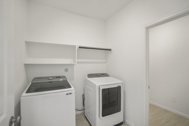 laundry area with washing machine and clothes dryer, baseboards, and light wood-type flooring