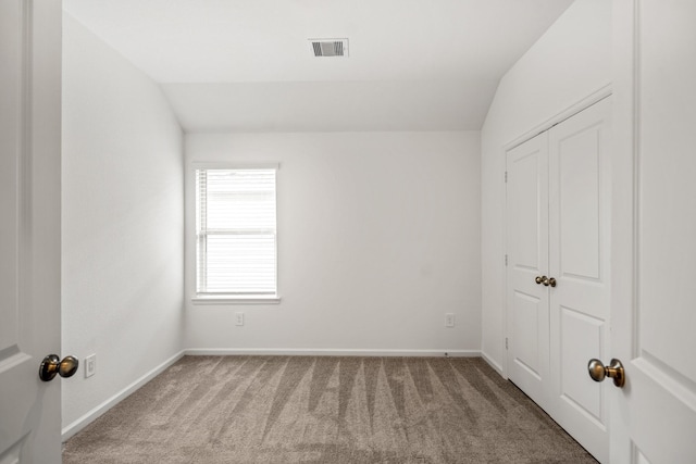 spare room featuring carpet flooring, baseboards, and lofted ceiling