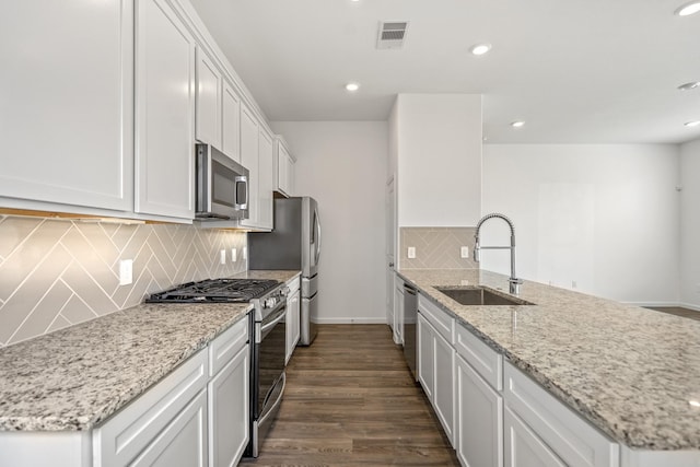 kitchen featuring stainless steel appliances, a sink, a peninsula, baseboards, and white cabinets