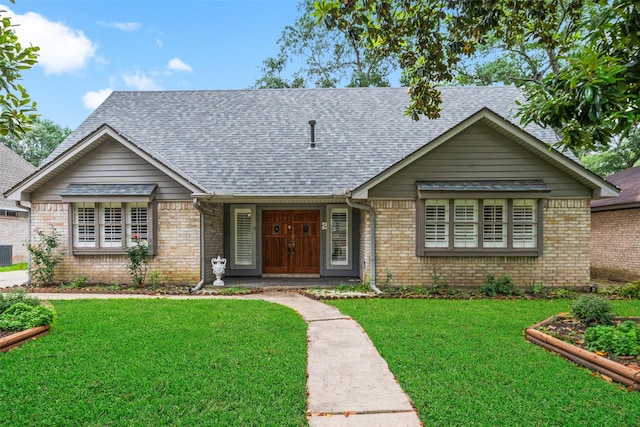 single story home with a front lawn, roof with shingles, and brick siding