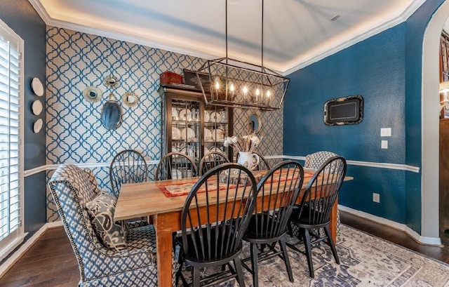 dining area with ornamental molding, baseboards, an accent wall, wood finished floors, and wallpapered walls